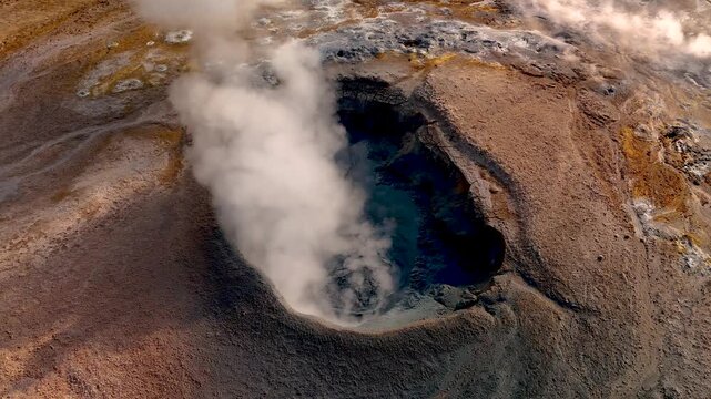 Steam billows from a deep volcanic crater in Iceland, showcasing the raw power of nature. This breathtaking geothermal feature highlights the unique landscape and vibrant colors of Hverir Myvatn