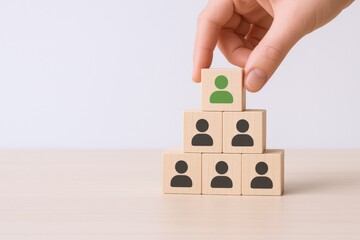 Hand Placing Wooden Block with Leader Icon on Top of Pyramid: Leadership Concept