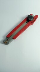 Red Utility Knife with Metal Blade and Adjustable Safety Lock on White Surface