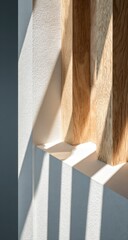 Sunlight streams through a light-filled window, casting shadows on a white wall.  Wooden beams frame the window