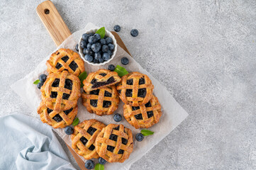 Homemade blueberry hand pies or mini tarts with milk on a concrete background.