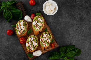 Halloween food. Avocado toasts with mozzarella in the shape of skulls and balsamic sauce on top. Funny food idea. Top view, copy space.