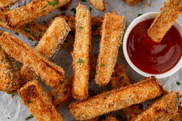 Baked crispy eggplant sticks served with tomatoes sauce. Vegetarian healthy dish. Selective focus, top view.