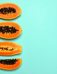 Four papaya slices arranged vertically against a teal background