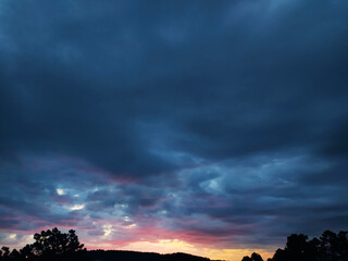 Dramatic sky with moody, dark clouds illuminated by soft sunset hues. Evokes emotion, atmosphere,...