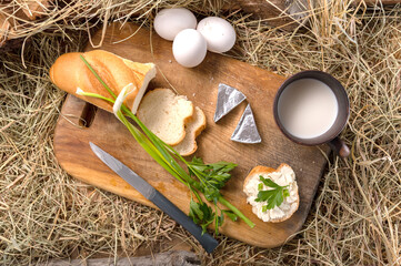 Breakfast preparation scene with sandwich, eggs, and milk on hay. Rustic snack with cheese, fresh...