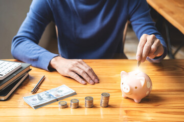 Young man putting coins into piggy bank planning growing saving to strategy with money box for...