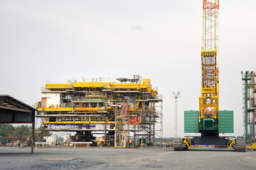 Oil rig under construction onshore. To assemble steel structure platform by big crane lifting,...
