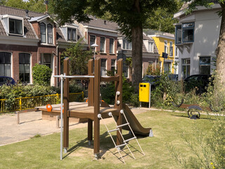 Playground equipment in urban park setting, featuring slide and climbing structure, signaling end...