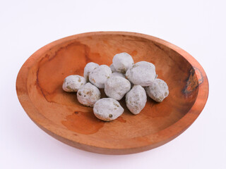 Spoiled candlenuts covered with mold, showing a white fuzzy layer and spots of decay, indicating...