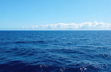 Fototapeta premium Serene ocean scene with light blue sky and fluffy white clouds. Darker blue ocean with small waves. Horizon line clearly visible. Bird eye view of vast expanse of water. Ocean blue and white