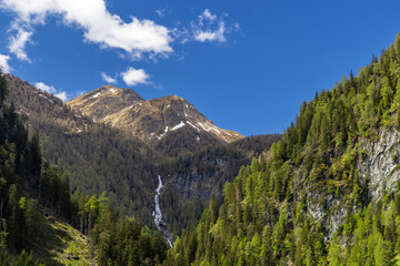 Obraz premium Waterfall cascading down rocky mountainside in Austrian Alps near Pragraten am Grosvenediger