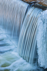Winter landscape of the Portage Creek cascade framed by ice and captured with motion blur, Michigan, USA