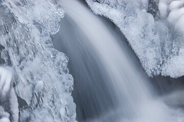 Winter landscape of the Orangeville Creek cascade framed by ice and captured with motion blur, Michigan, USA