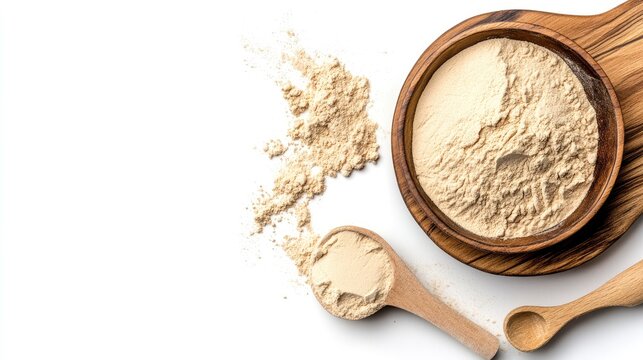 Maca powder in wooden bowl with spoon and spilled powder on white background