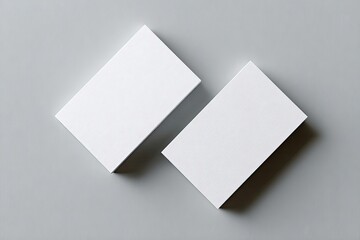 Two blank white business cards, slightly angled, on a neutral gray background