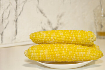 Three cooked cob of sweet corn on white plate against background. Tasty sweet corn on cob.