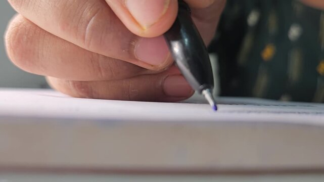 Close-up hands of student writing with pen on notebook. Concept of studying and academic work.