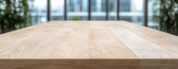 Smooth wooden table surface with natural finish, set in modern interior space filled with greenery and large windows, creates serene atmosphere