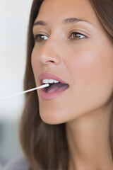 A woman is using a cotton swab to take an oral sample, mouth slightly open. Healthcare, DNA test, analysis, examination
