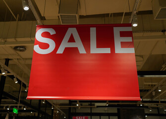 Red sign announces start of sale in store for shopping. Discount sale label at shop entrance. Concept of shopping during discounts on mid year sale