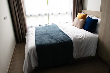 Interior with white bed linen. Bedroom with bed, white bedding with sunlight shines through white...