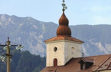 A beige-colored church steeple with a brown roof sits majestically against the backdrop of the...