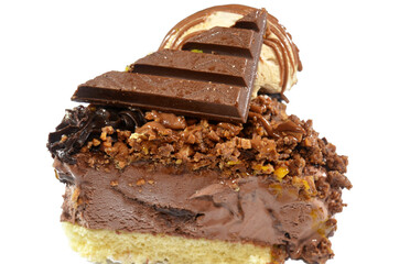 A Piece of ice cream ball with chocolate sauce and wafer on a piece of an Ice cream cake, on a sponge cake layer, topped with chocolate pieces and cream and sauce, chunks of chocolates with pistachio