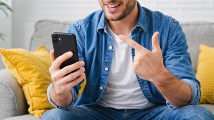 Joyful Connection - Man Sharing Exciting Moment on Phone, A warmly lit, close-up shot capturing a man's genuine excitement while using his smartphone. Dressed casually in a denim shirt and jeans.
