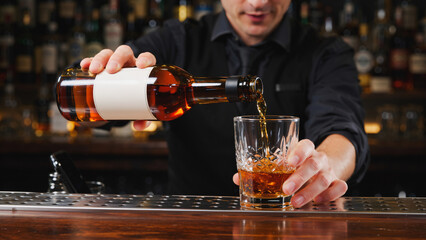 The Art of the Pour Whiskey Craftsmanship, A close-up, moody photograph showcasing a bartender&rsquo;s skillful pour of amber whiskey into a classic tumbler.
