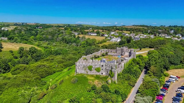 A rotating aerial view around the old Norman castle ruins at the seaside resort of Manorbier, South Wales in summertime