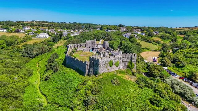 A full semicircle rotating aerial view around the old Norman castle ruins at the seaside resort of Manorbier, South Wales in summertime