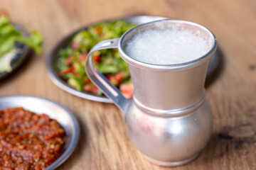 Macro shot of local Turkish ayran in a gray copper glass on a wooden background	