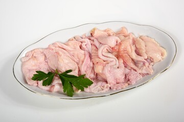 Raw chicken skin pieces on a white plate on a white background