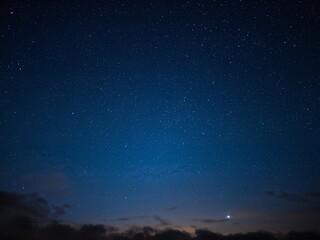 Fototapeta premium A beautiful night sky full of stars with clouds at the horizon. A concept for astronomy, space, or tranquility.