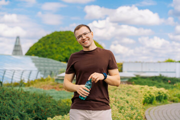 Smiling man holding a water bottle outdoors