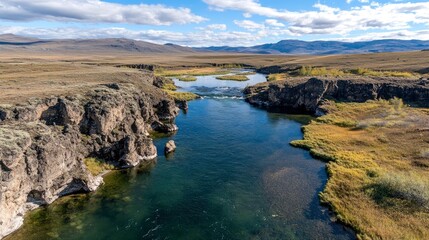 Fototapeta premium Aerial view of a deep river canyon with rocky cliffs and distant mountains.