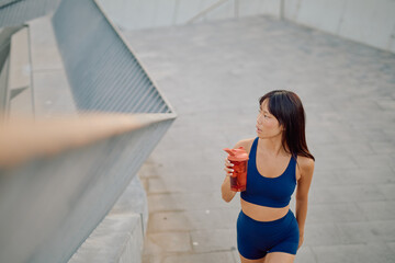 Asian athlete enjoying a refreshing protein shake after an intense workout session in the bustling...