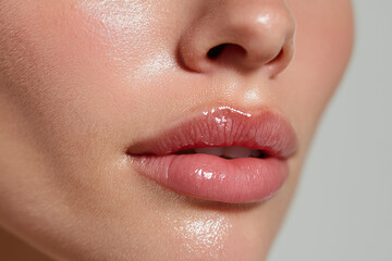 Fototapeta premium Glossy hydrated lips and smooth cheek skin close up beauty shot showing natural texture and healthy glow with soft lighting and neutral background