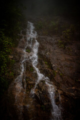 Waterfall cascading down rocky cliff in tropical forest of Vietnam.