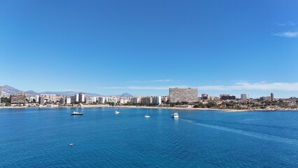 Fototapeta premium Panoramic view of a coastal city with modern buildings, sandy beach and clear blue sea under a bright sunny sky