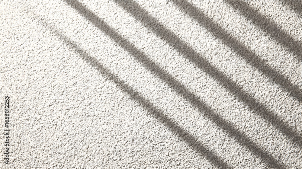 Poster diagonal shadows cast by window blinds on a textured, light-gray surface create a subtle pattern.
