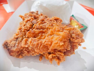 Close-up of a fried chicken with a crispy texture skin, delicious with authentic seasoning at a fast food restaurant. Served with rice and sauce