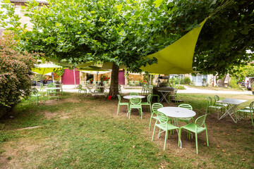 Outdoor cafe tables and chairs standing on green lawn in Saint Jean de Cole, France