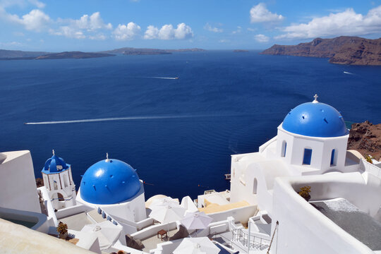 Oia village on Santorini island, Greece. Traditional and famous church with blue domes and white houses over the Caldera, Cyclades islands Aegean sea.