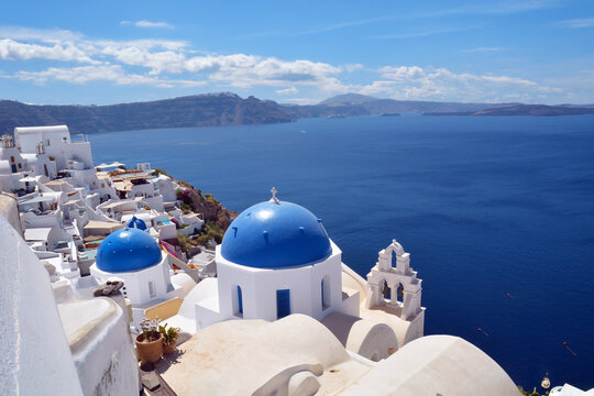 Oia village on Santorini island, Greece. Traditional and famous church with blue domes and white houses over the Caldera, Cyclades islands Aegean sea.