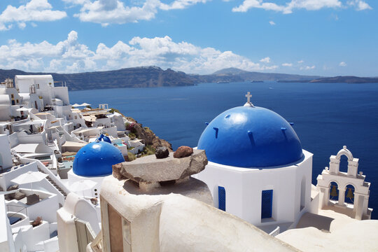 Oia village on Santorini island, Greece. Traditional and famous church with blue domes and white houses over the Caldera, Cyclades islands Aegean sea.