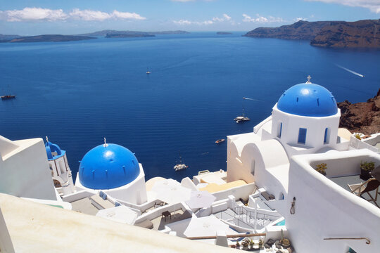 Oia village on Santorini island, Greece. Traditional and famous church with blue domes and white houses over the Caldera, Cyclades islands Aegean sea.