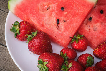 watermelon slices and strawberries lie on a white plate