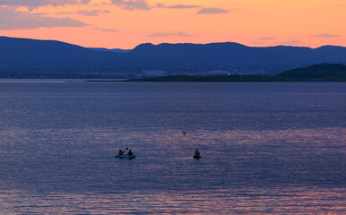 Aerial view of Purple and orange sunset scene of Oslofjord and mountain with people playing sup board in the water, Oslo, Norway